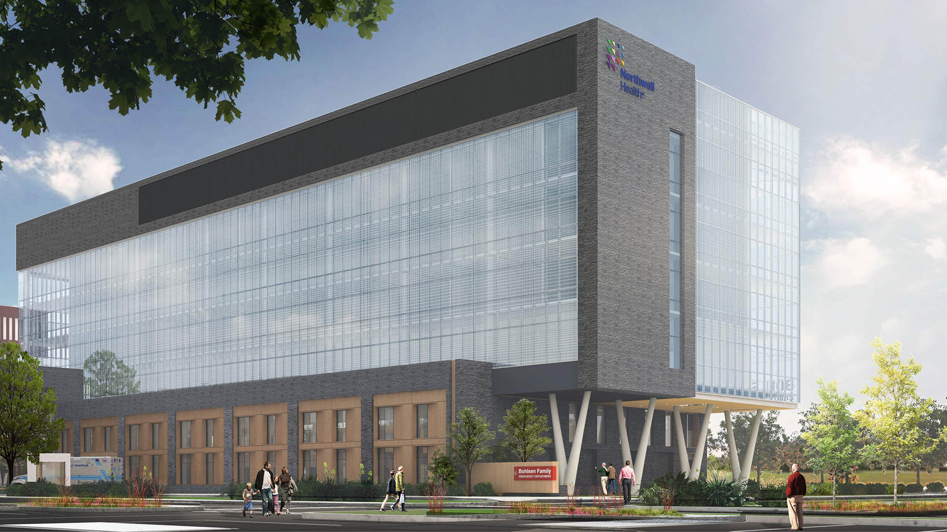 A modern, multi-story healthcare building with large glass windows and a brick facade. Several people walk on the sidewalk outside, and trees and greenery are visible around the structure.