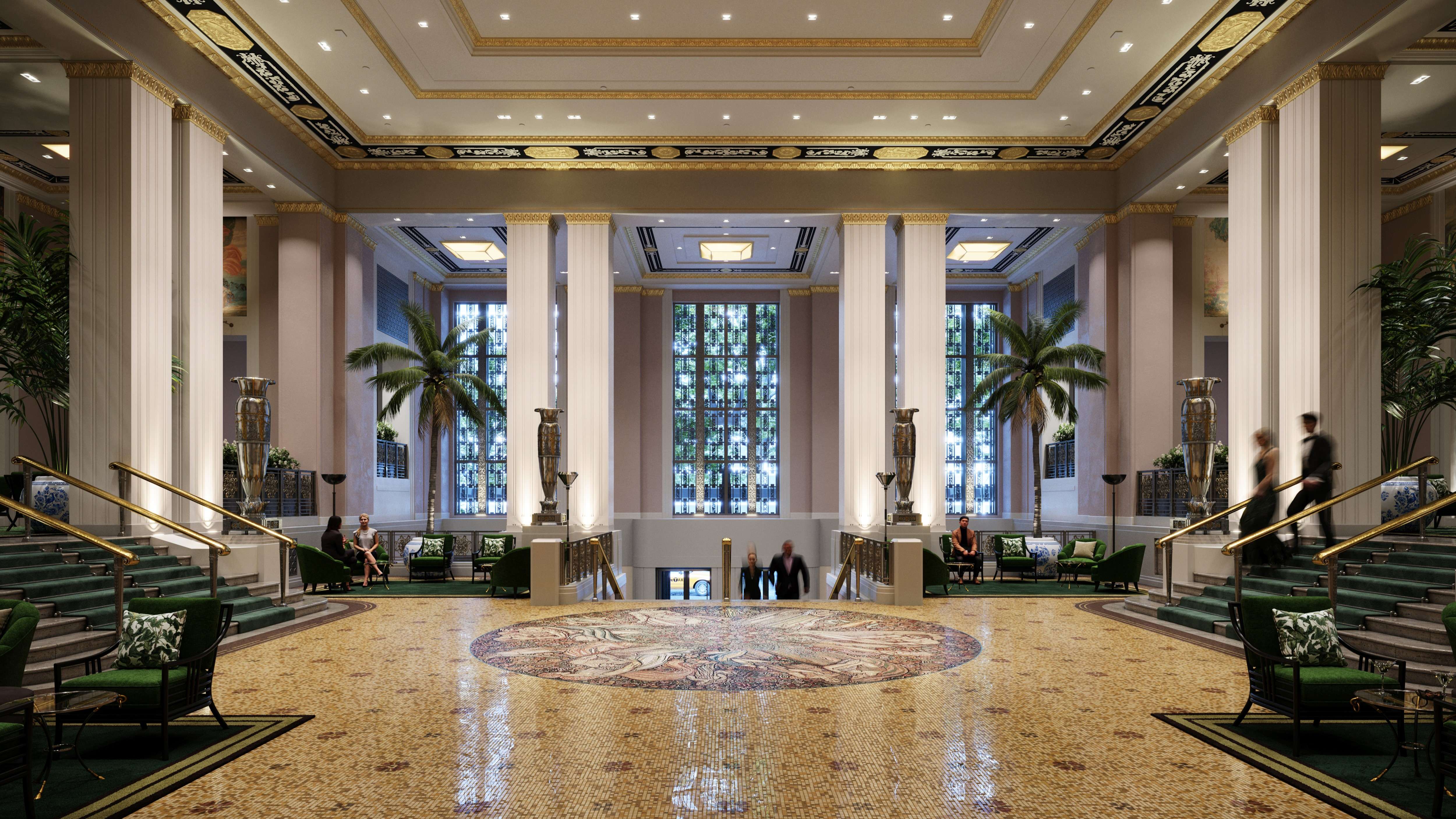 A grand hotel lobby with tall columns, indoor palm trees, a mosaic floor, and wide staircases. Large windows let in natural light, and people are seated or walking through the elegant, spacious area.