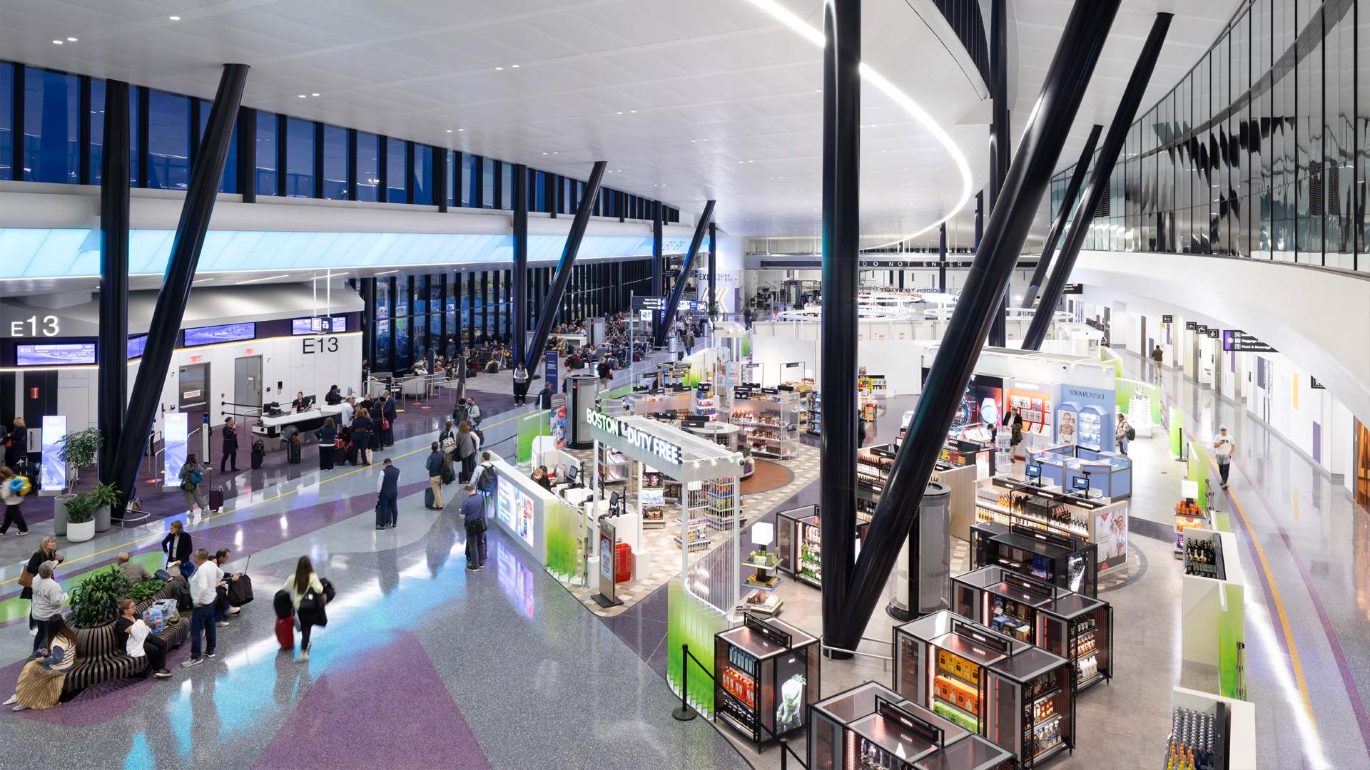A modern aviation terminal with high ceilings, shops, seating areas, and passengers walking or waiting near boarding gates E13 and E14. Large windows let in natural light, creating a bright and spacious transportation hub.