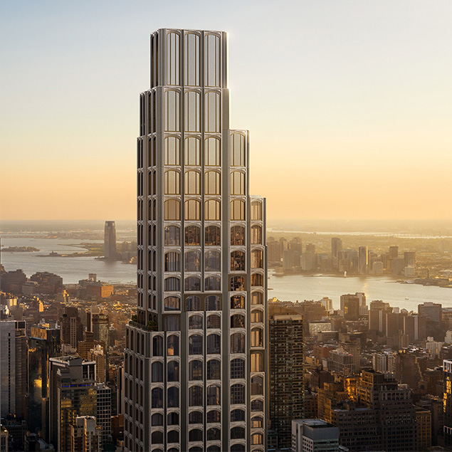 A tall, modern skyscraper with a tiered design and large windows stands prominently above a cityscape at sunset, with a river and distant buildings visible in the background.