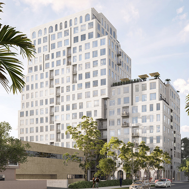 A modern, multi-story white building with many windows and balconies, surrounded by trees and palm trees, under a partly cloudy sky. Cars and people are visible in the foreground.