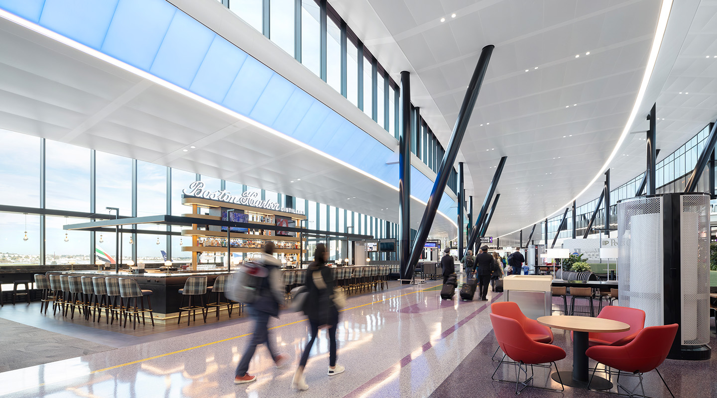 A modern airport terminal with high ceilings, large windows, and travelers from various sectors walking through a bright space featuring a bar area, seating with red chairs and tables, all in a sleek, contemporary design flooded with natural light.
