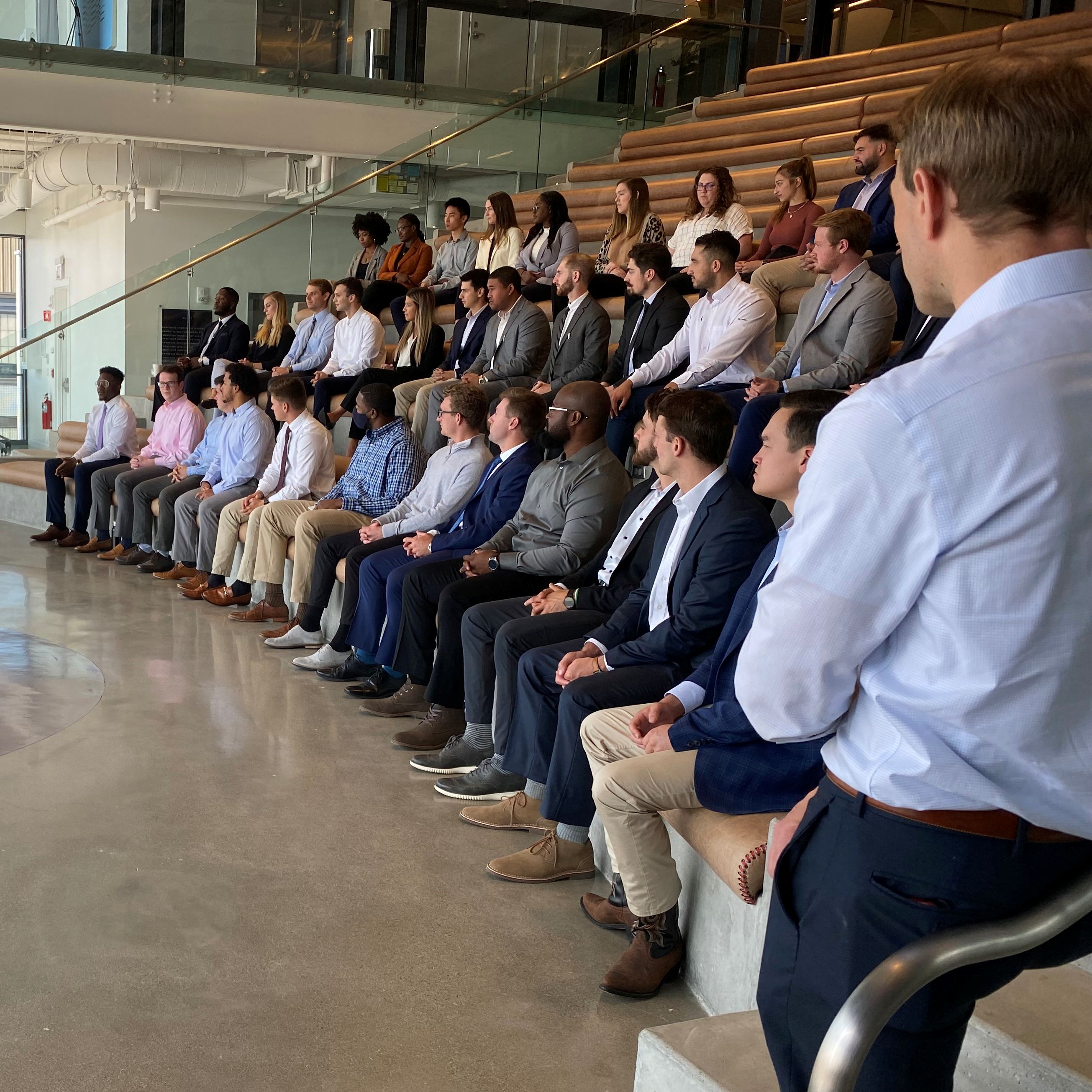 photo of group of people sitting on bleachers looking away from camera learning