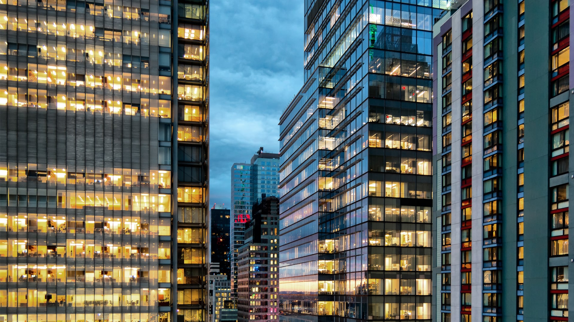 cityscape at dusk with office building windows with lights on