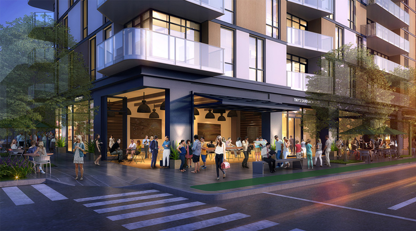 A modern apartment building with large glass windows and balconies, featuring a lively street-level café where people gather, dine, and socialize by outdoor tables near a crosswalk and trees in the evening light.