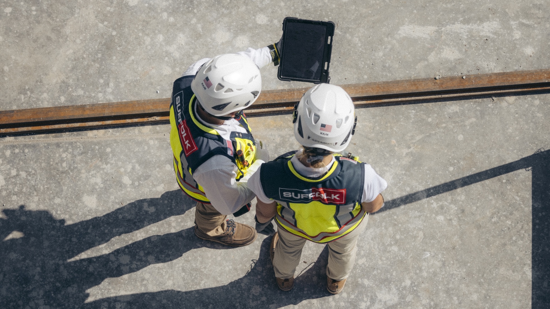 aerial view of 2 suffolk workers looking at ipad with full gear on