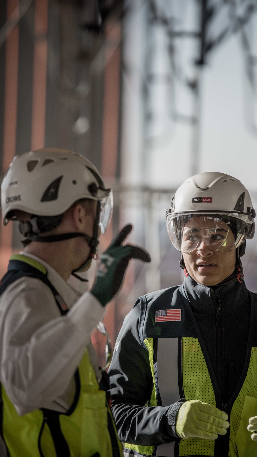 close up of two suffolk workers talking one pointing at something off screen