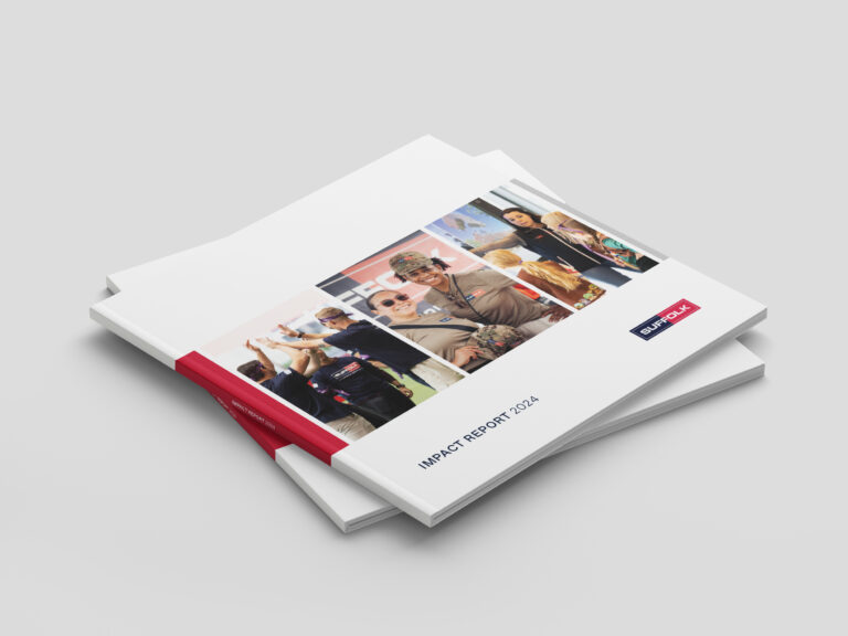 A stack of Impact Report 2024 booklets with a white cover, featuring a collage of diverse people interacting and a red logo labeled Blue Owl on the front. The booklets are placed on a light gray surface.