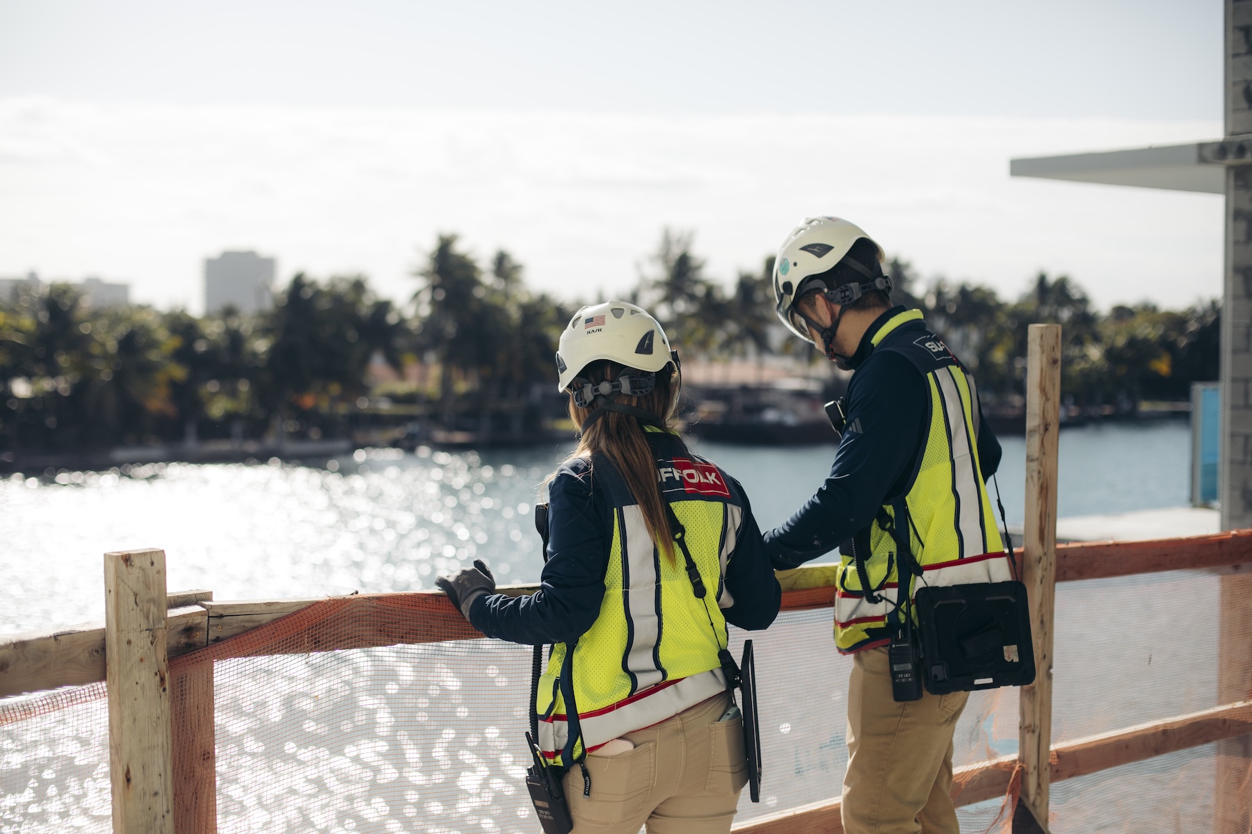 two suffolk construction workers in bright vests looking out at water