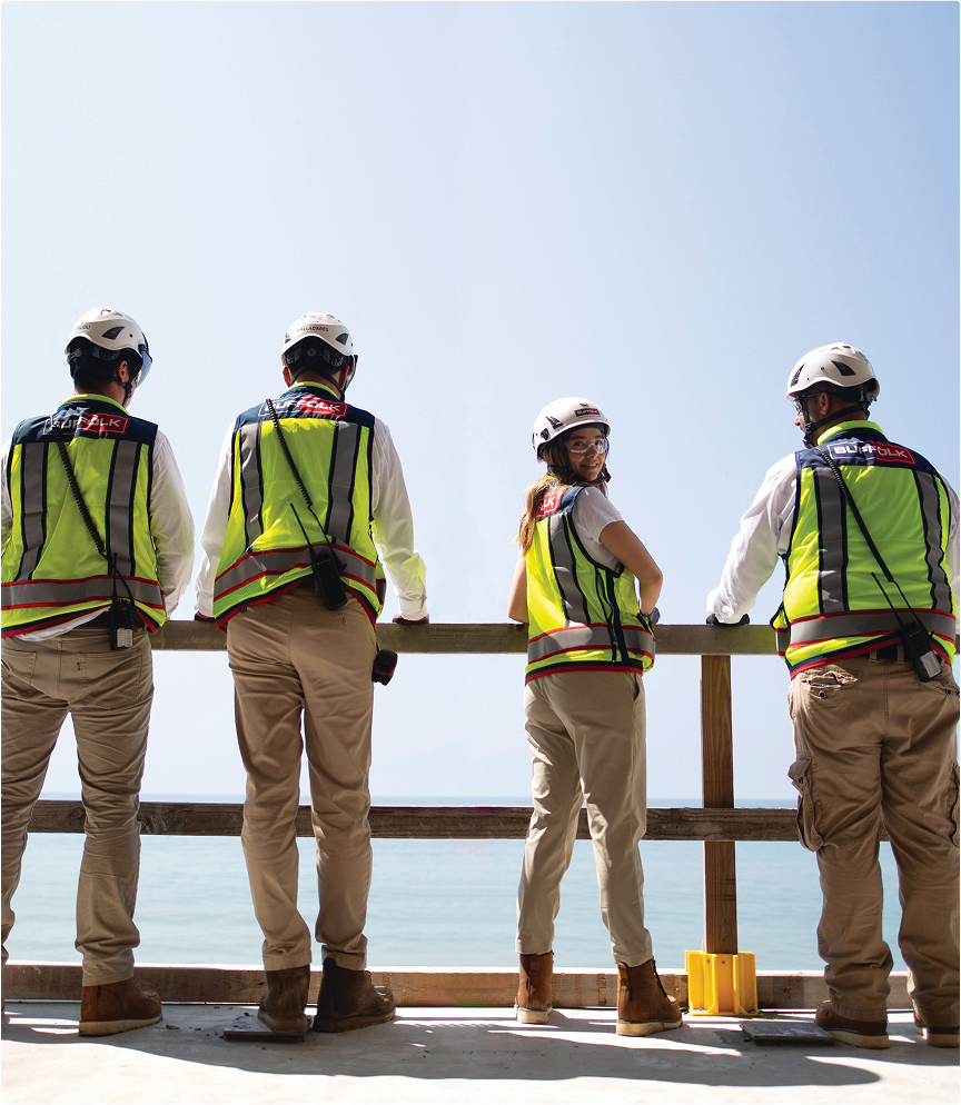 4 suffolk workers from behind looking out at the view of the sky one turned to face the camera
