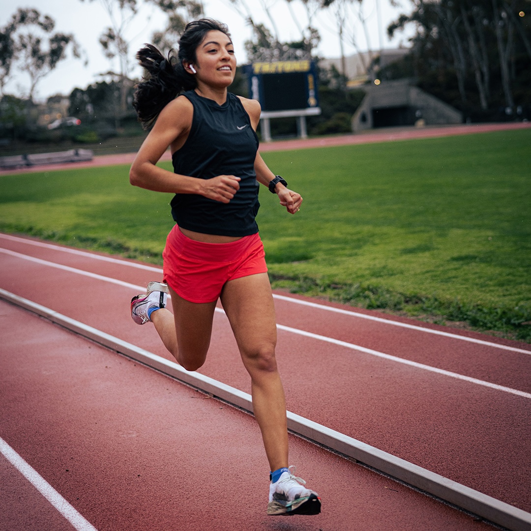 woman running on a track smiling