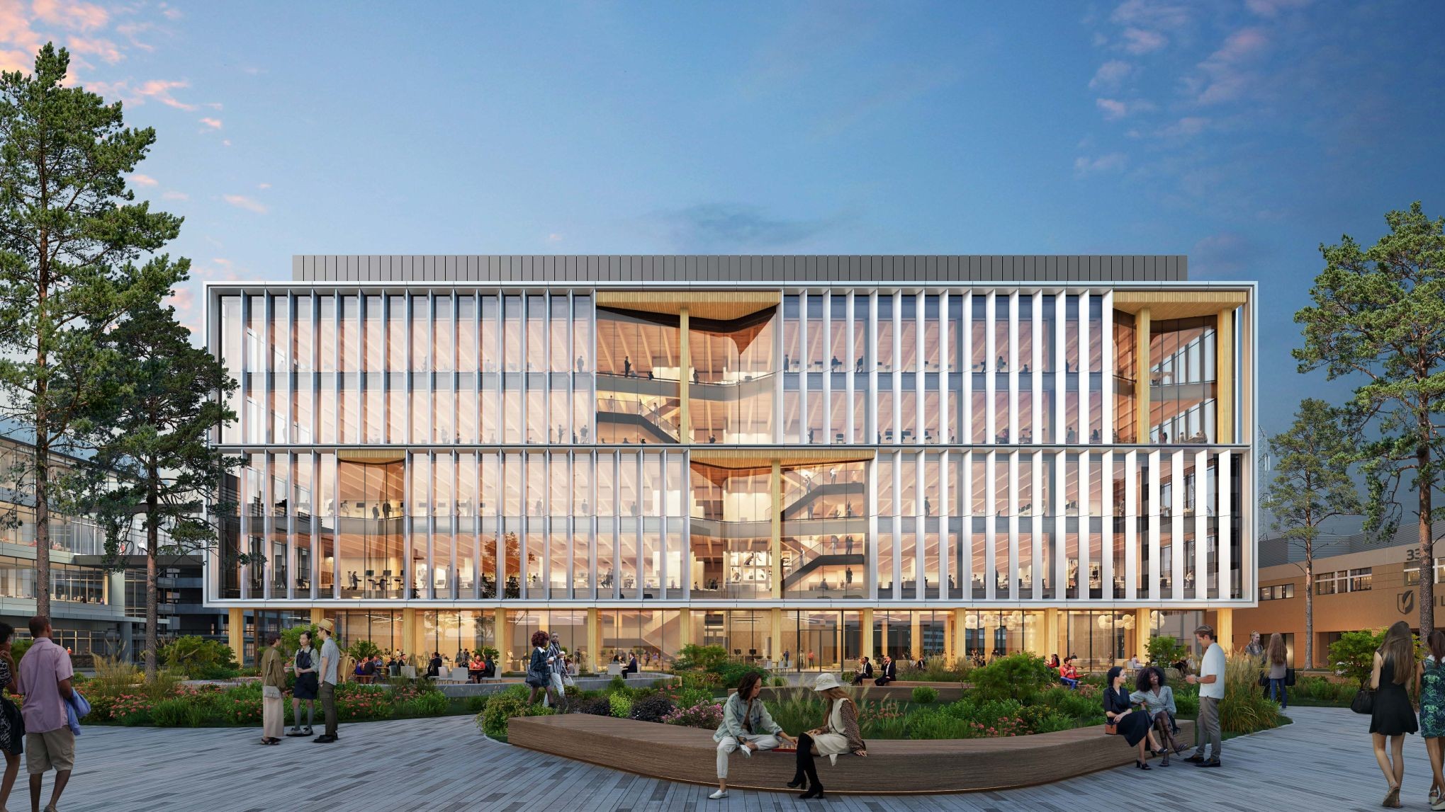 A modern, multi-story building with large glass windows and vertical white slats, surrounded by trees and landscaped gardens where people are walking, sitting, and socializing under a blue sky.